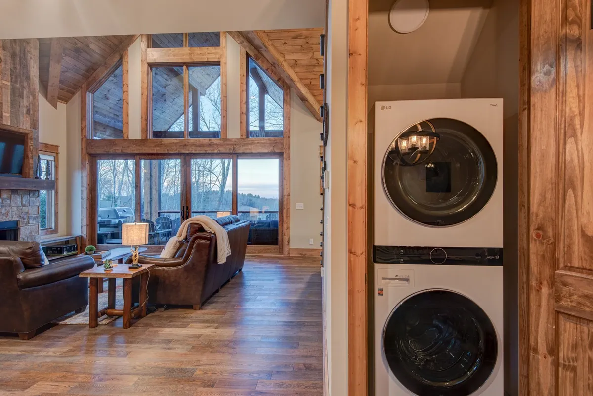 A spacious seating area framed by large windows, wooden accents, and a warm fireplace offers a soothing vantage point for taking in the mountain views. The image evokes comfort while visually connecting the interior to the surrounding landscape.