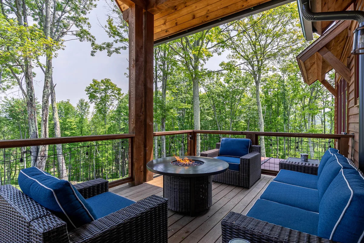 A cozy fire pit area encircled by comfortable outdoor seating is set among tall trees. The setup invites families to gather for stories, marshmallow roasting, and relaxation under the open sky.